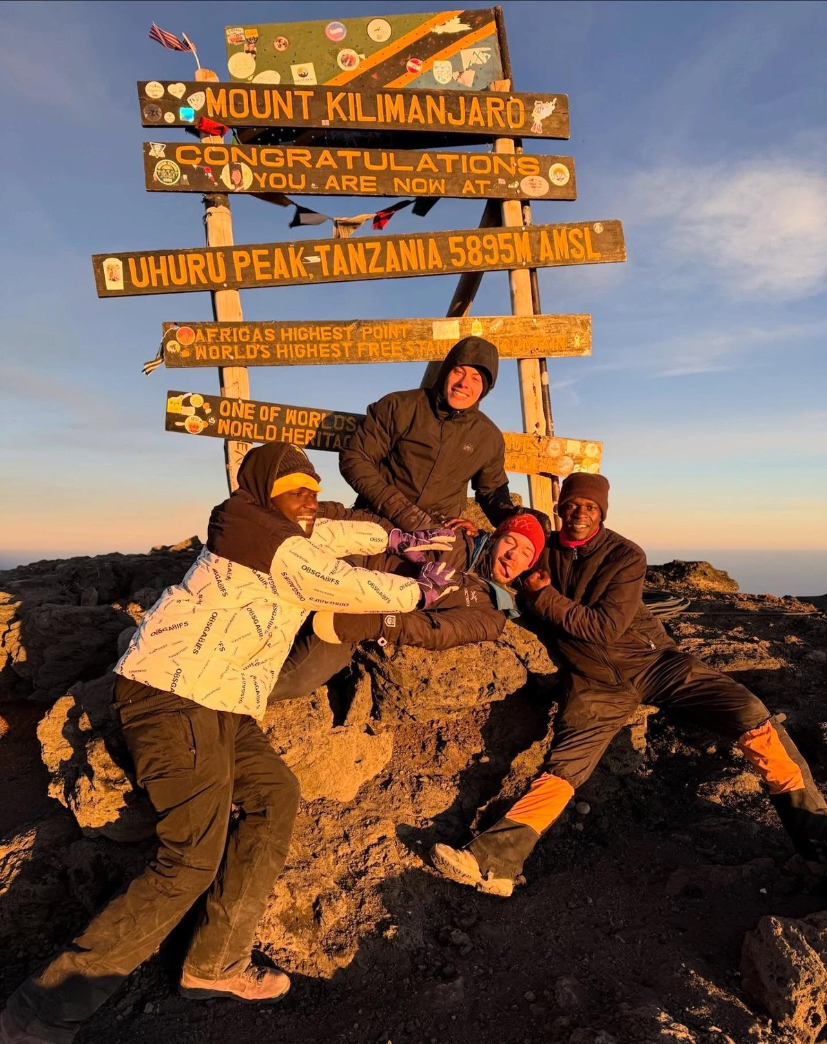 Drake and guides at the Kilimanjaro summit sign