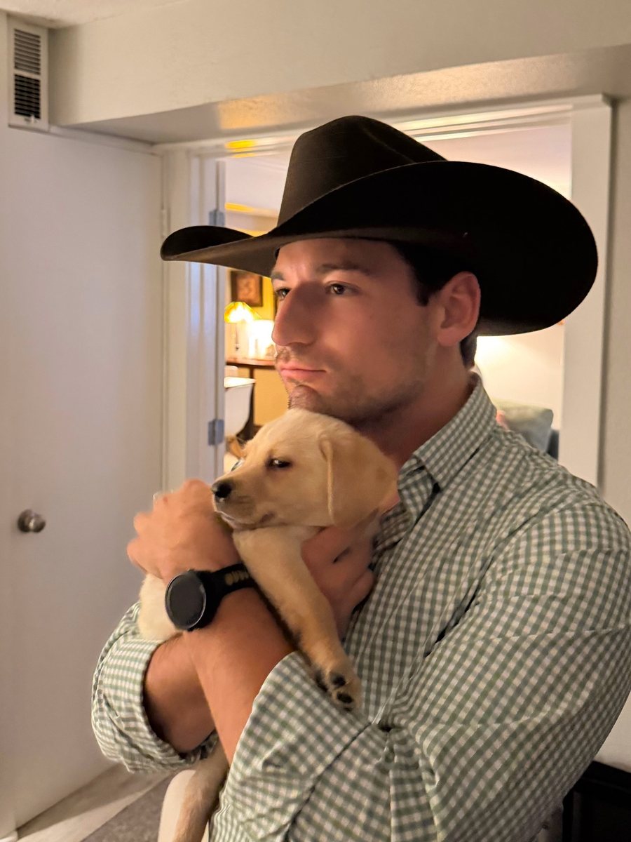 Drake in a cowboy hat holding a puppy