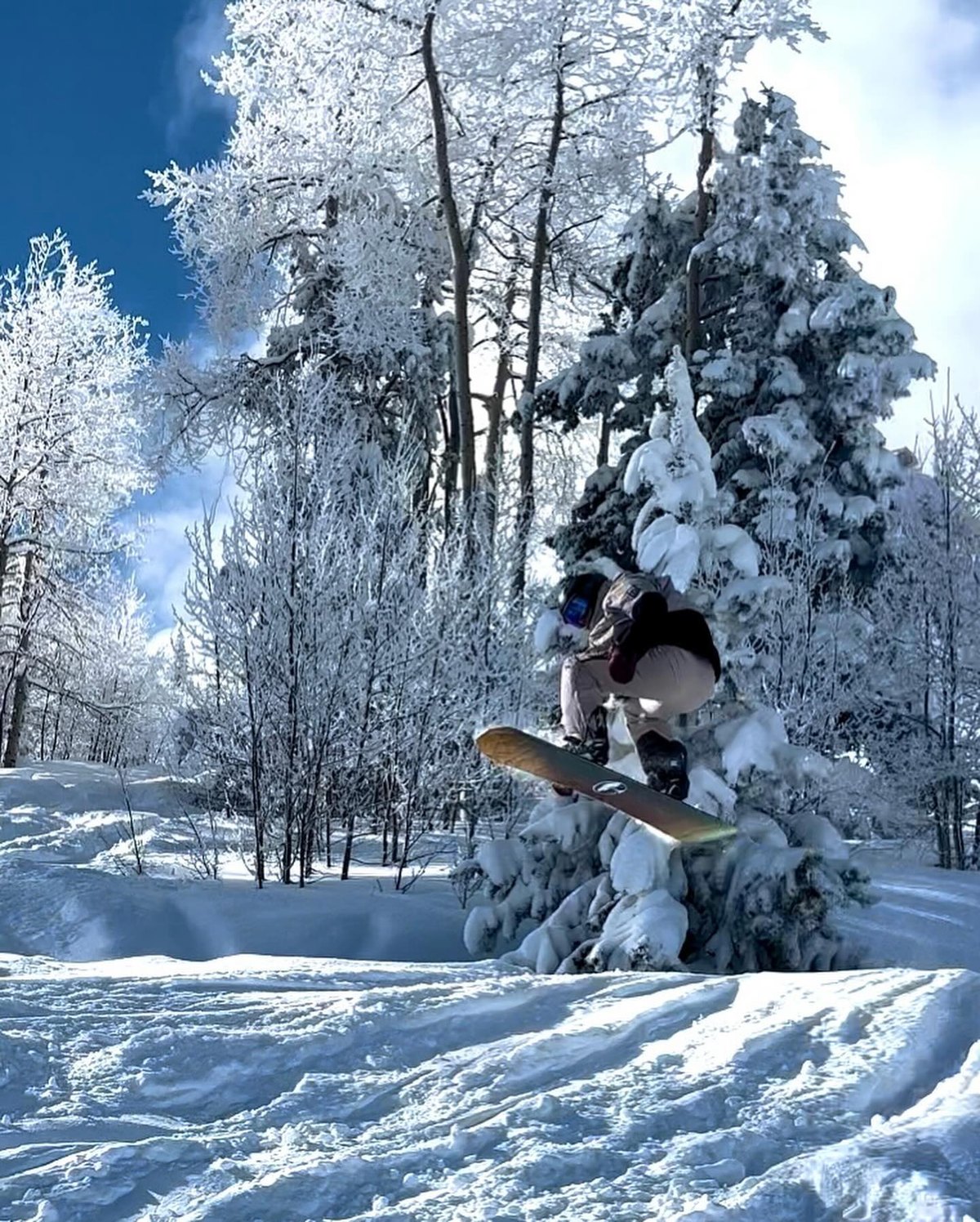 Drake snowboarding off a jump in fresh powder